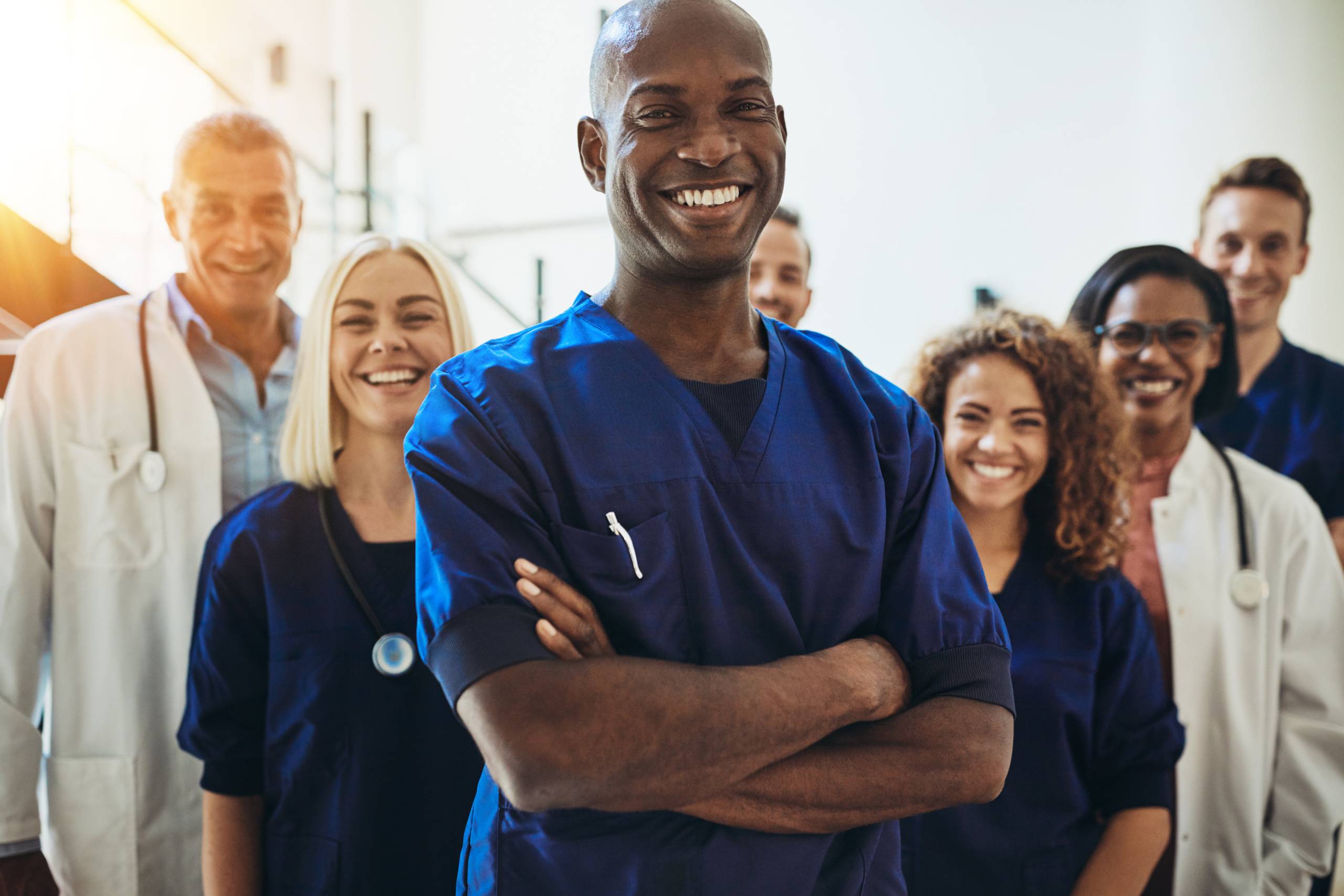 Diverse team of smiling healthcare professionals standing confidently together in clinical uniforms.